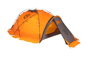 The NEMO Equipment Chogori™ Mountaineering Tent is a bright orange and gray, dome-shaped four-season tent with multiple support poles, an extended vestibule, and a visible NEMO logo. One of its flaps is partially open.